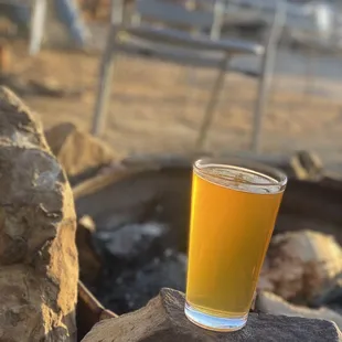 a glass of beer sitting on a rock