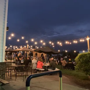 people sitting at tables under string lights