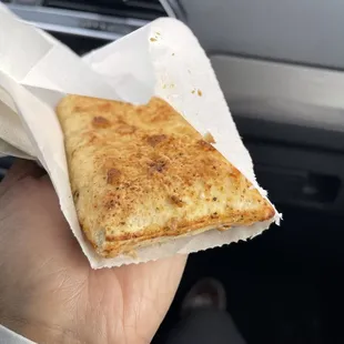 a hand holding a piece of pizza