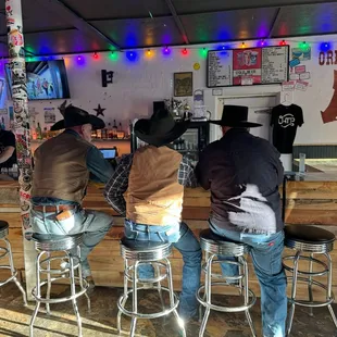 three men sitting at a bar