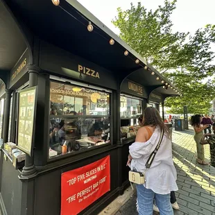 a woman standing in front of a pizza shop
