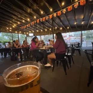 a woman sitting at a table with a glass of beer