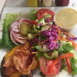 Bacon cheeseburger with cheddar cheese and a side salad with honey mustard dressing