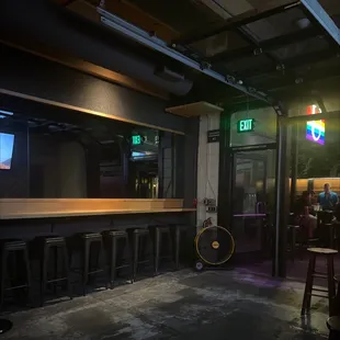 a view of a bar with stools and a neon sign