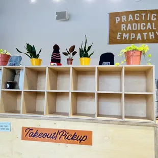 a wooden counter with potted plants and a sign that reads practice radical empathy