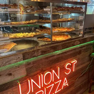 a pizza counter with a neon sign
