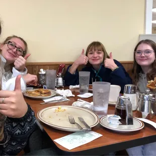 a group of women sitting at a table with plates of food