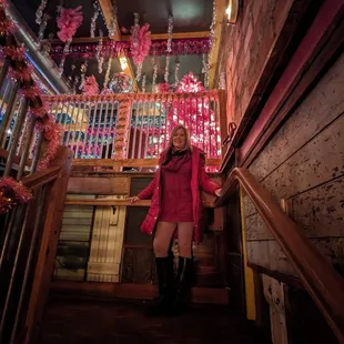 a woman in a pink coat and boots standing on the stairs