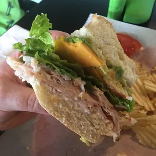 a hand holding a sandwich with lettuce and cheese