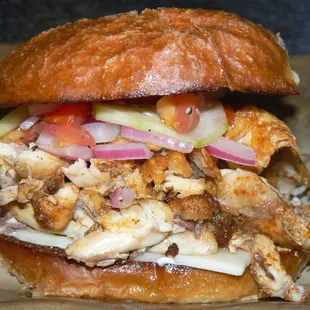 Chicken Hot Wings Deboned, Swiss Cheese, Pickled Cucumber, Red Onion, and Tomato, Mayonnaise on a Buttered and Grilled Egg Bun.