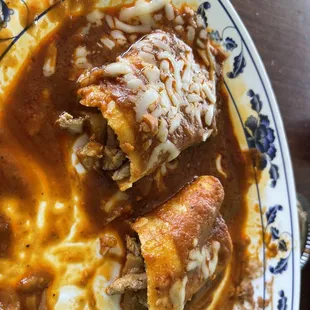 Two chicken enchiladas over soaked in the sauce for the nice portion of grated cheese and a side of beans and rice approximately $12