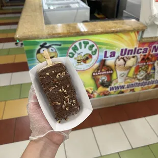 chocolate covered vanilla popsicle with pecan toppings