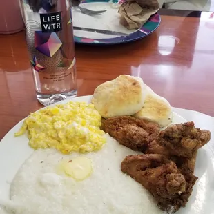 Grits eggs fried chicken and biscuits.