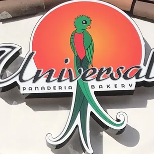 a green bird perched on a sign