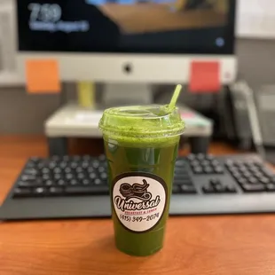 a green smoothie in front of a computer