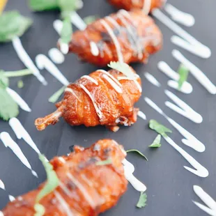 a plate of chicken wings covered in sauce and garnished with cilantro