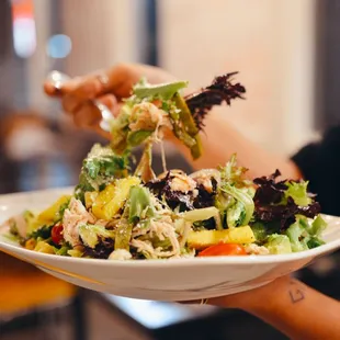 a person holding a plate of salad