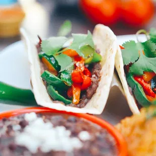 a plate of tacos and a bowl of beans