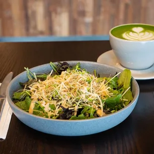 a bowl of salad and a cup of cappuccino
