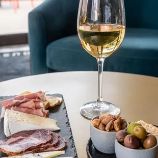 a glass of wine and a plate of meat and cheese