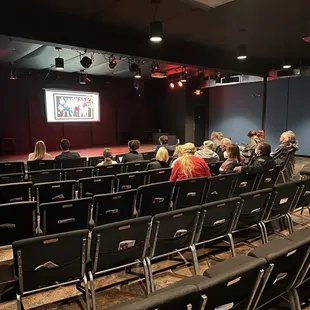 people sitting in chairs in front of a projector screen