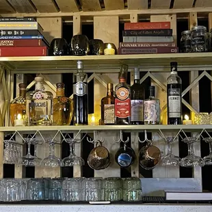 a shelf of wine glasses and bottles