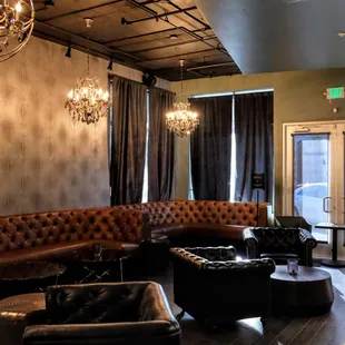 a living room with leather couches and chandeliers