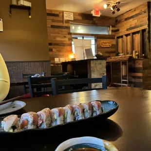 a plate of sushi and a bowl of dipping sauce