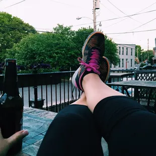 a person's feet on a table with a bottle of beer