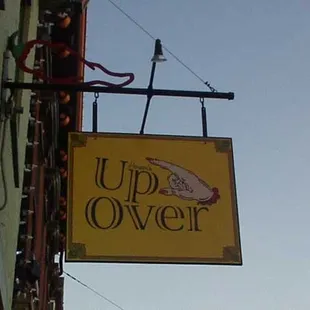 a yellow sign hanging from the side of a building