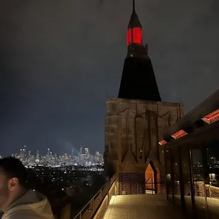 a man standing on a roof with a view of a city at night