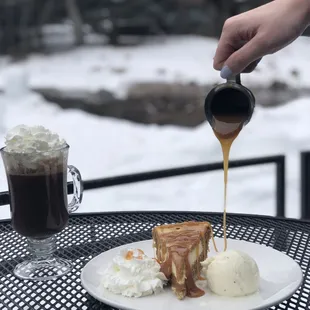 a person pouring caramel sauce over a piece of cake