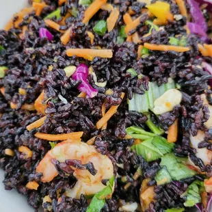 a plate of black rice salad with shrimp and carrots