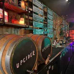a bar with barrels and neon signs