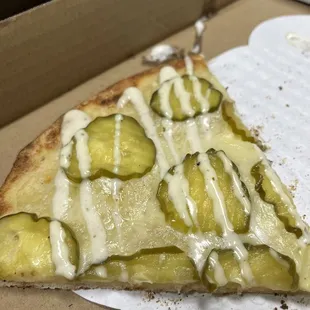 a slice of pizza with pickles on it