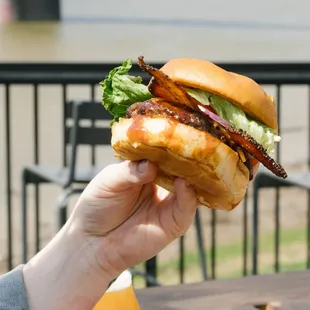 a hand holding a sandwich with bacon and lettuce