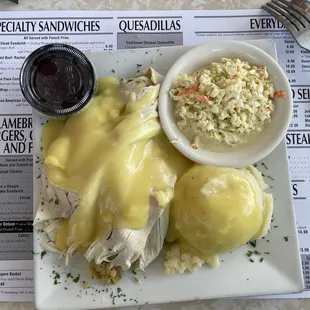 Roast turkey entrée with two sides atop stuffing. Mashed potatoes and coleslaw with a side of cranberry sauce.