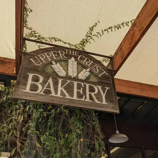 Old style wooden sign hanging above the outdoor seating area.
