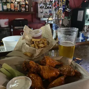 a tray of chicken wings, celery, and beer