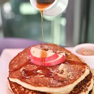 a stack of pancakes being drizzled with syrup