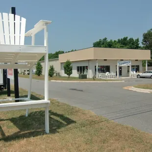11' White InfinityWood Adirondack Chair at entrance to Upscale Furniture Resales at 100 Le Bleu Avenue in Powells Point, NC.