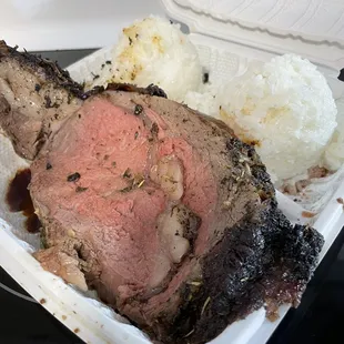 a roast of beef and rice in a styrofoam container