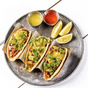 a plate of tacos with salsa and lime wedges