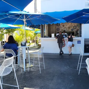 a group of people sitting under blue umbrellas