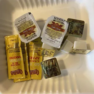 Condiments butter, syrup, hot sauce and utensils
