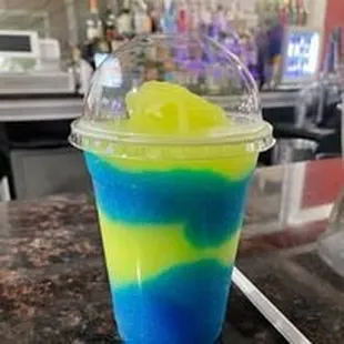 a blue and yellow drink in a plastic cup