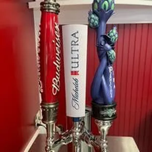 three beer taps with a red wall behind them