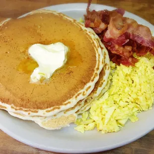 3 stack pancakes with pork bacon and scrambled eggs. Blueberry and Strawberry toppings available too!