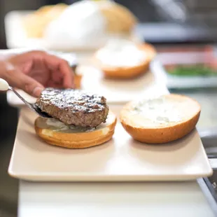 a person cutting a burger on a plate