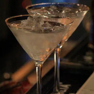 two martini glasses on a bar